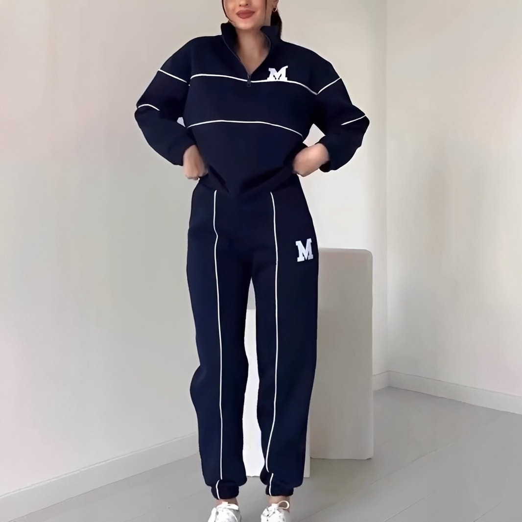 Person wearing a navy tracksuit with white accents in a minimalistic room.